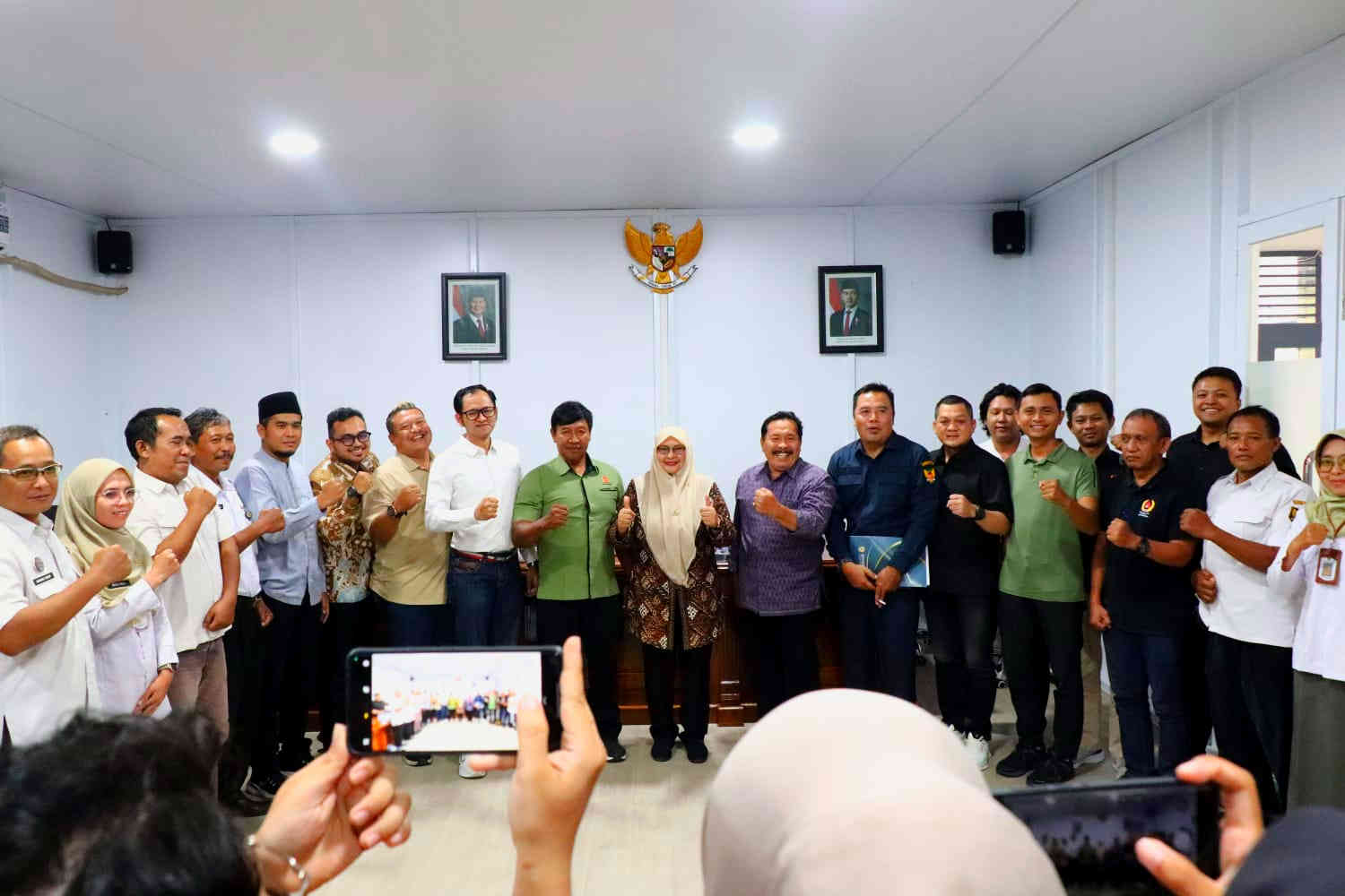 Foto bersama jajaran pengurus KONI Kota Kediri dan anggota DPRD Kota Kediri dengan pose mengepalkan tangan sebagai simbol komitmen olahraga di akhir acara audiensi.
