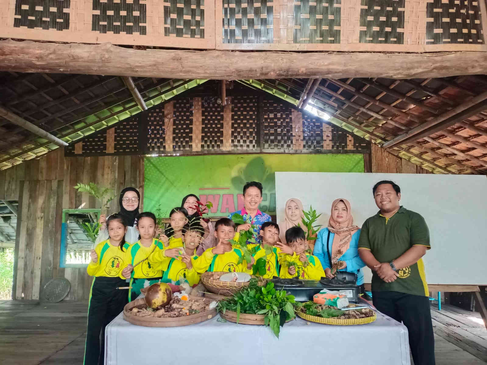 Siswa kelas 3 SDN Tosaren 1 Kota Kediri berfoto bersama guru sambil memegang tanaman obat tradisional dan rempah dalam kegiatan kokurikuler di Wahyu Alam.