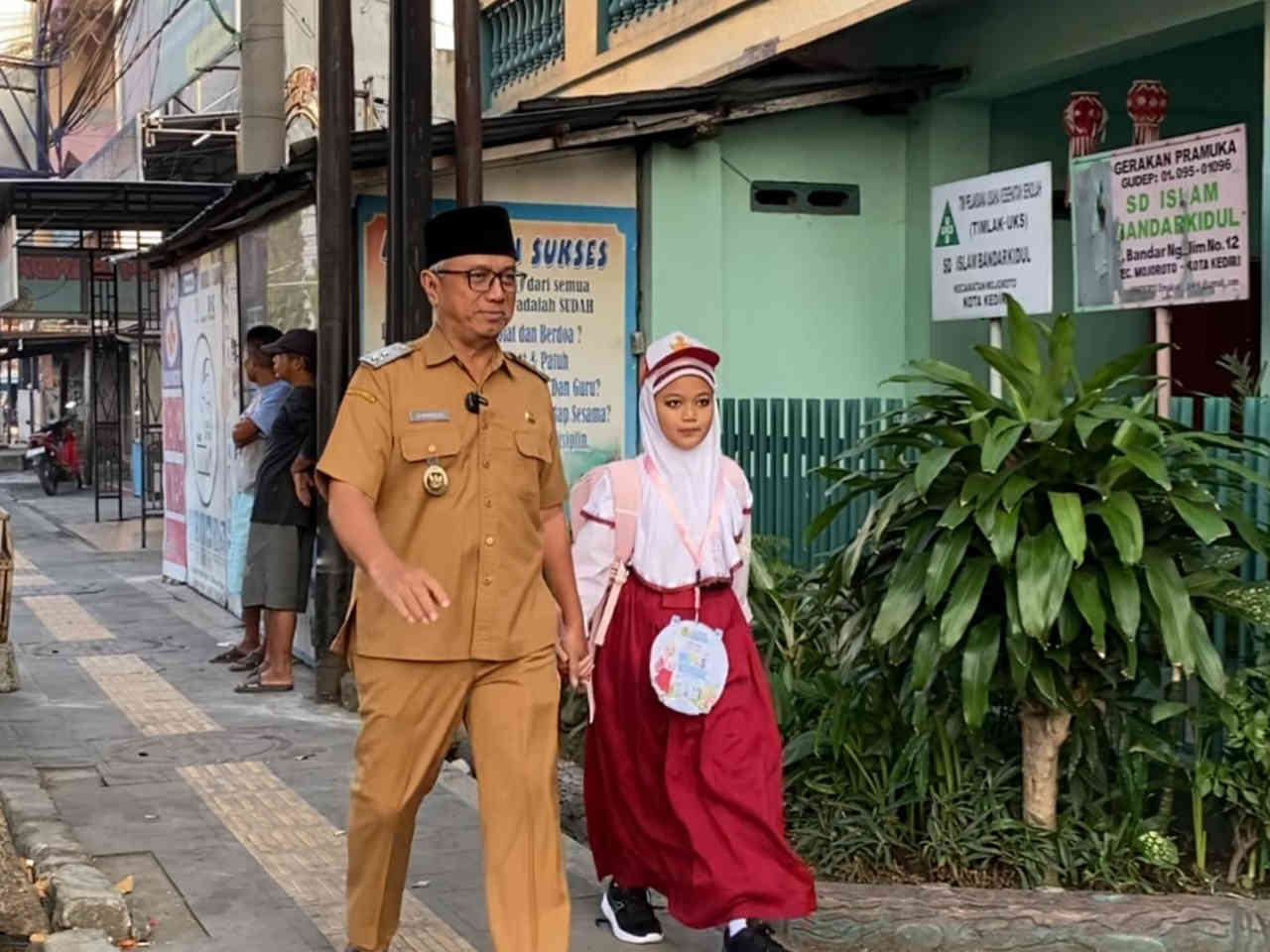 Wakil Wali Kota Kediri KH Qowimmudin Thoha (Gus Qowim) mengenakan seragam dinas ASN saat berjalan kaki mengantar putrinya ke sekolah SD Islam Bandarkidul pada hari pertama tahun ajaran baru.