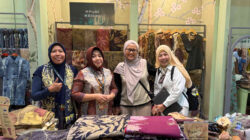 Empat wanita, termasuk perwakilan UMKM batik binaan KPwBI Kediri dan pejabat BI Kediri, tersenyum bangga di depan stan pameran penuh kain batik dan ecoprint berkualitas.