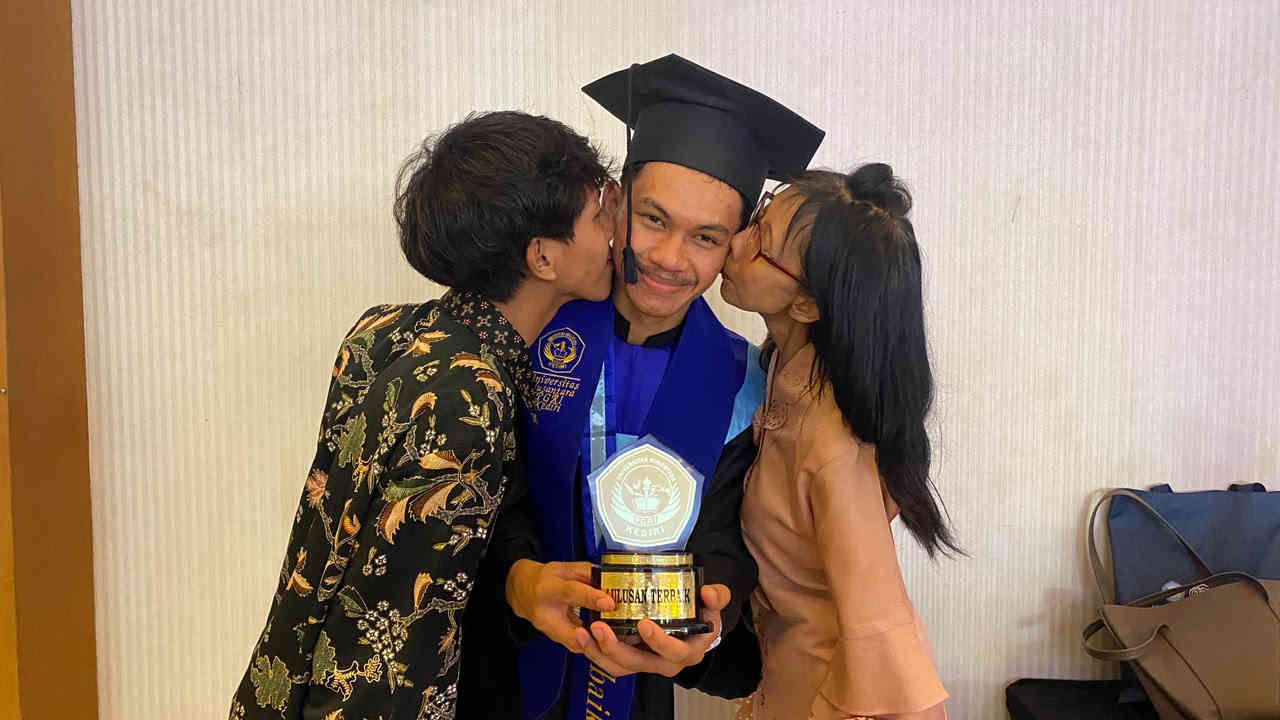 F. Irfando Jovan Kantur, wisudawan terbaik UNP Kediri dengan IPK 3,96, berfoto bersama ibu dan saudaranya saat wisuda.